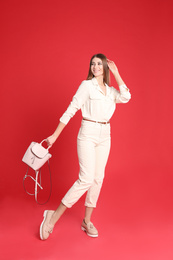 Photo of Beautiful young woman in casual outfit with stylish bag on red background