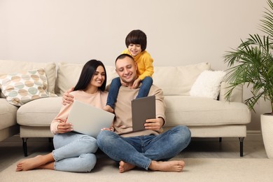 Photo of Happy family with gadgets on floor at home