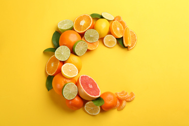 Letter C made with citrus fruits on yellow background as vitamin representation, flat lay