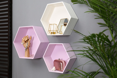 Hexagon shaped shelves with different stuff on grey wall. Interior design