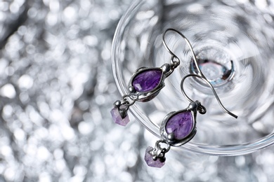 Beautiful pair of silver earrings with amethyst gemstones on blurred background, above view