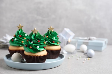Christmas tree shaped cupcakes on light grey table. Space for text