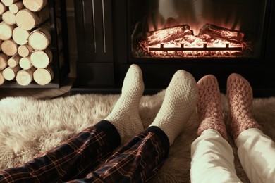 Couple in knitted socks near fireplace at home, closeup of legs