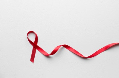 Photo of Red awareness ribbon on white background, top view with space for text. World AIDS disease day
