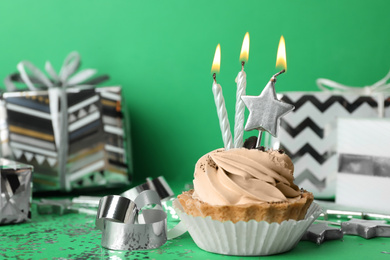 Birthday cupcake with candles on green background