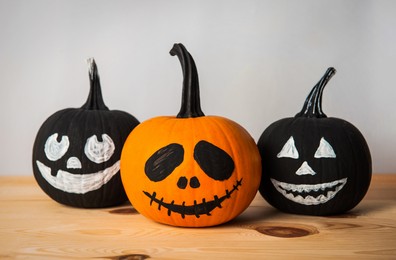 Halloween celebration. Pumpkins with spooky drawn faces on wooden table