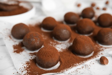 Delicious chocolate truffles powdered with cocoa on white table, closeup