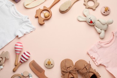 Frame of baby clothes and accessories on light pink background, flat lay. Space for text