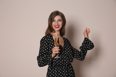 Happy woman with champagne on beige background. Christmas party