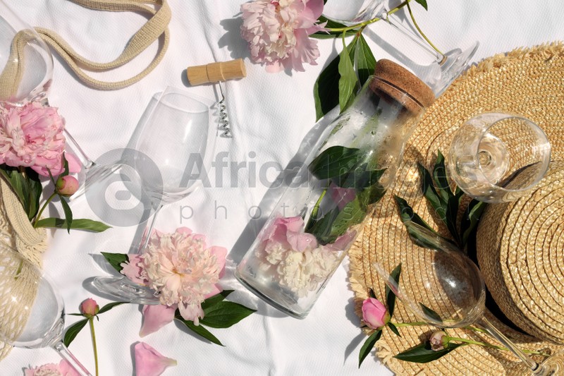 Photo of Flat lay composition with beautiful peonies and wineglasses on white fabric