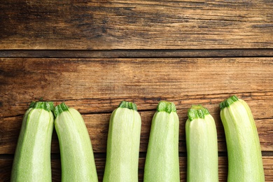 Raw green zucchinis on wooden table, flat lay. Space for text