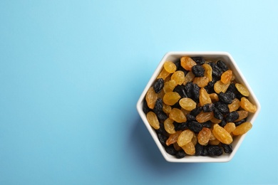 Bowl of raisins on color background, top view with space for text. Dried fruit as healthy snack