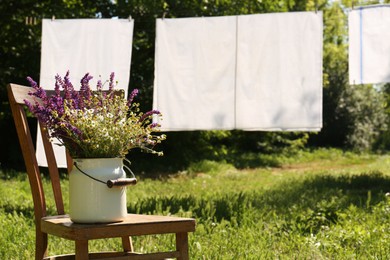 Photo of Beautiful bouquet with field flowers on chair outdoors, space for text