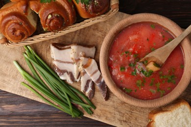 Photo of Delicious borsch served with pampushky and salo on wooden table, top view. Traditional Ukrainian cuisine