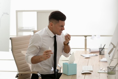 Ill businessman with nasal spray table in office