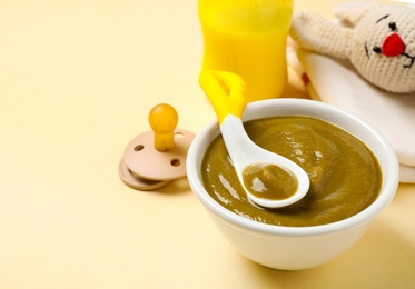 Bowl of healthy baby food on yellow background. Space for text
