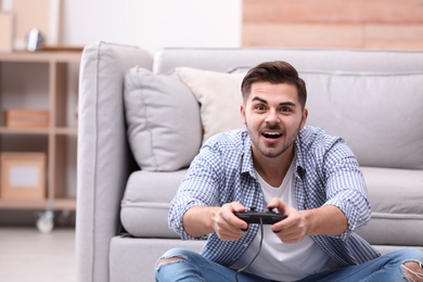 Emotional young man playing video games at home