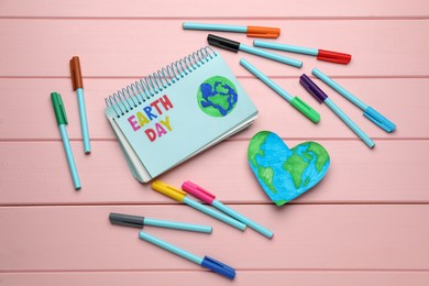 Happy Earth Day. Flat lay composition with notebook and markers on pink wooden table