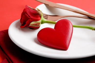 Elegant table setting for romantic dinner on red background, closeup. Valentine's day celebration