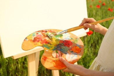 Little girl painting on easel in countryside, closeup