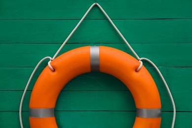 Orange lifebuoy hanging on green wooden wall. Rescue equipment