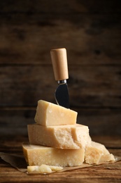 Delicious parmesan cheese and knife on wooden table