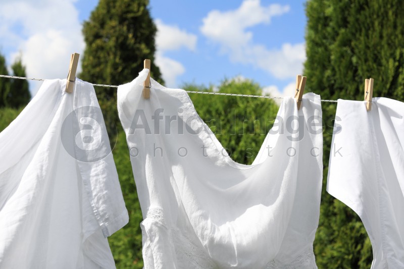 Photo of Clean clothes hanging on washing line outdoors, closeup. Drying laundry