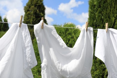 Clean clothes hanging on washing line outdoors, closeup. Drying laundry