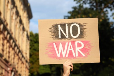 Photo of Woman holding poster with words No War outdoors