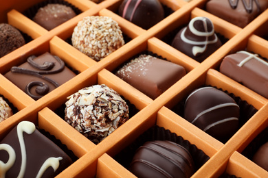 Box with different chocolate candies as background, closeup