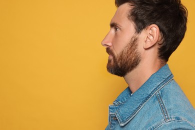 Photo of Profile portrait of bearded man on orange background. Space for text