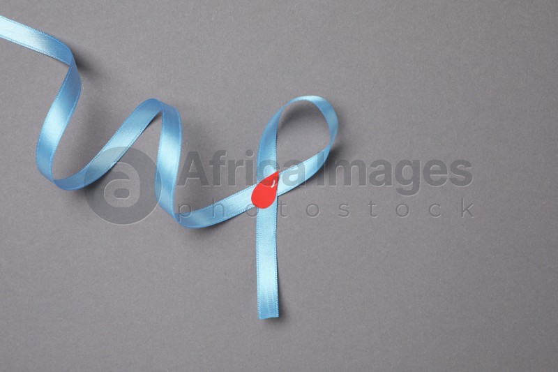 Light blue ribbon with paper blood drop on grey background, top view and space for text. Diabetes awareness