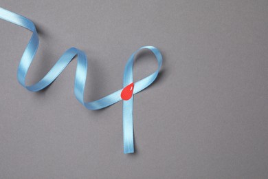 Light blue ribbon with paper blood drop on grey background, top view and space for text. Diabetes awareness