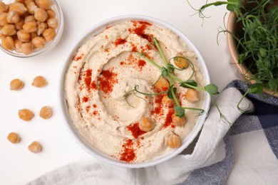 Delicious hummus with chickpeas and paprika served on white table, flat lay
