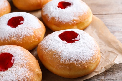Hanukkah doughnuts with jelly and sugar powder on wooden table, closeup