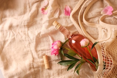 Flat lay composition with rose wine and beautiful peonies on beige fabric. Space for text