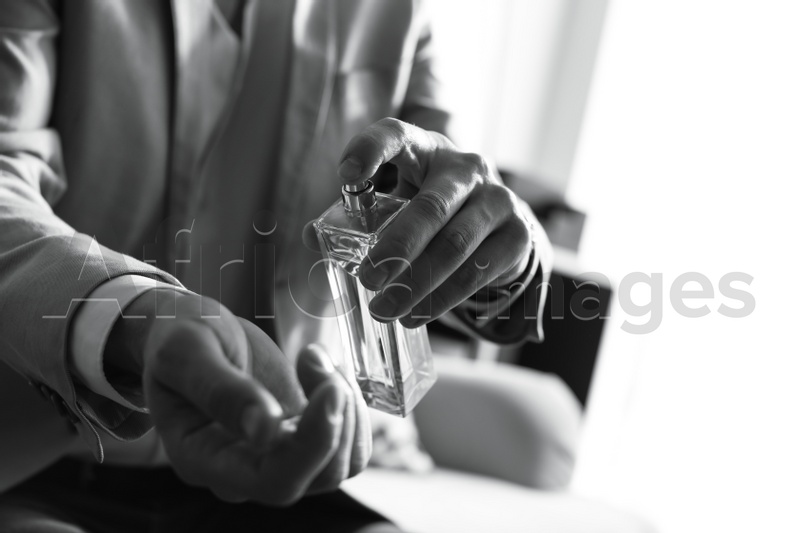 Man applying perfume on wrist indoors, closeup with space for text. Black and white effect