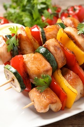 Delicious chicken shish kebabs with vegetables on table, closeup