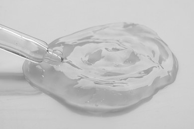 Dripping facial gel from pipette on white background, closeup
