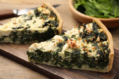 Photo of Pieces of delicious homemade spinach quiche on wooden table, closeup