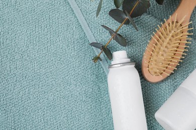 Dry shampoo sprays, hairbrush and eucalyptus branch on towel, flat lay. Space for text