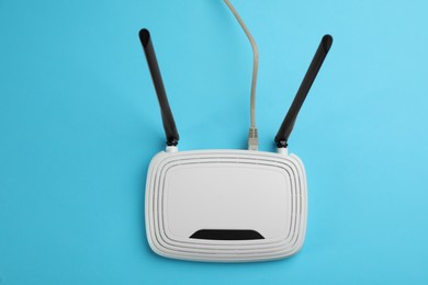 Modern Wi-Fi router on light blue background, top view