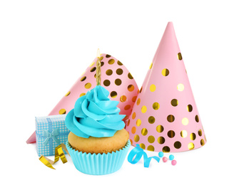 Delicious birthday cupcake with candle, gift and party caps on white background