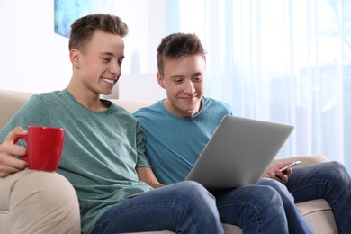 Teenage twin brothers together on sofa in living room