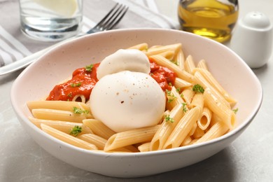 Delicious pasta with burrata cheese and sauce on light grey table