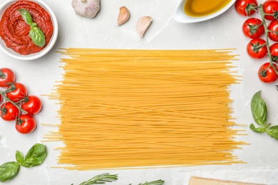 Beautiful composition with raw pasta and ingredients for sauce on table, top view