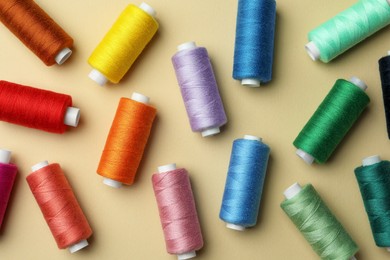 Photo of Flat lay composition with colorful sewing threads on beige background