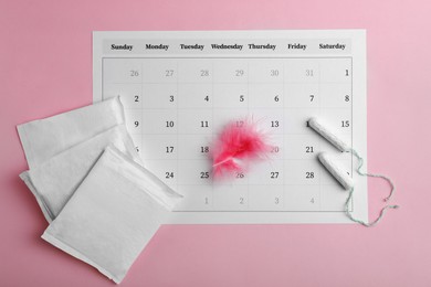 Menstrual pads, tampons, feather and calendar on pink background, flat lay