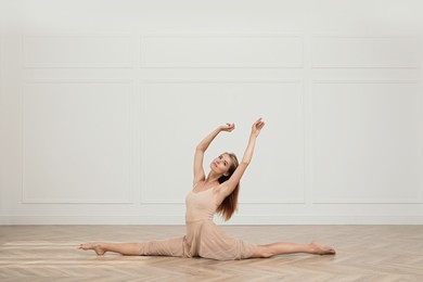 Beautiful professional dancer practicing split in studio