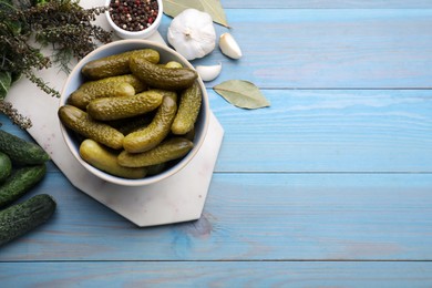 Photo of Fresh and pickled cucumbers with ingredients on light blue wooden table, flat lay. Space for text